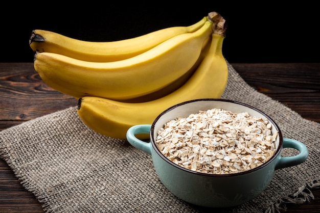 Banaan en havervlokken op donkere houten achtergrond.