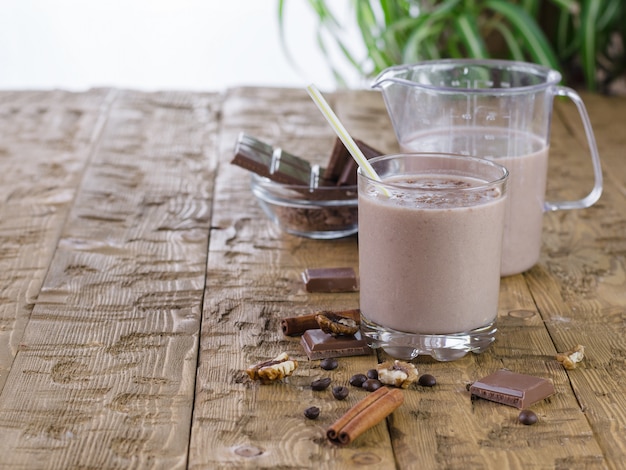 Banaan smoothie met kaneel en chocolade op rustieke tafel.