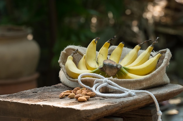 Photo banana and almond placed on a wooden table in the garden