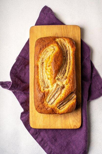 Banana bread on a wooden board, purple linen napkin