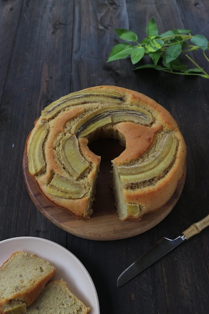 Foto torta alla banana guarnita con banane a fette su un tavolo di legno