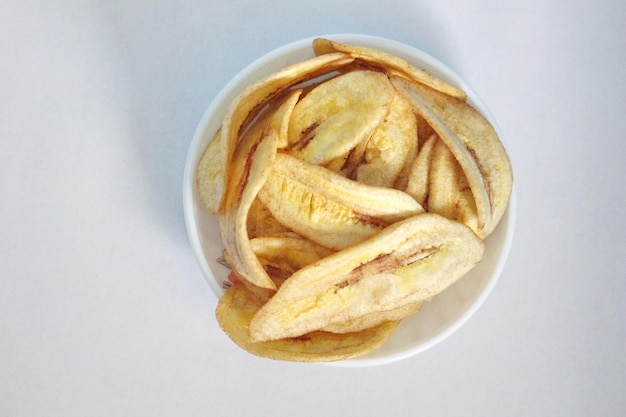 Banana chips in white bowl on a white background ready for sale