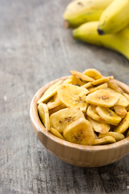 Banana chips in wooden bowl on wooden table