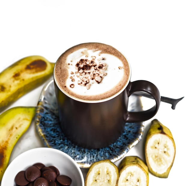 Banana chocolate latte with fresh banana and chocolate drops on white table