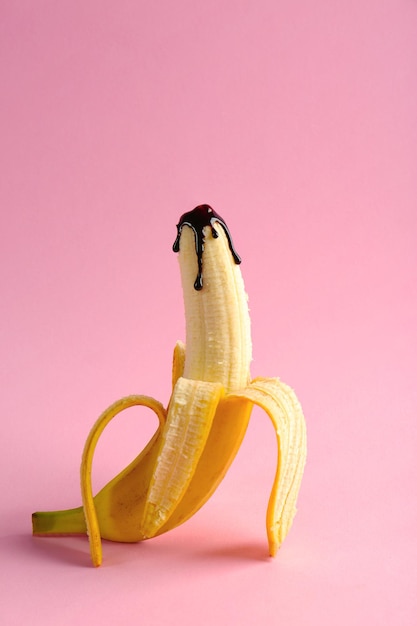 Banana covered with chocolate sauce on color background Sex concept