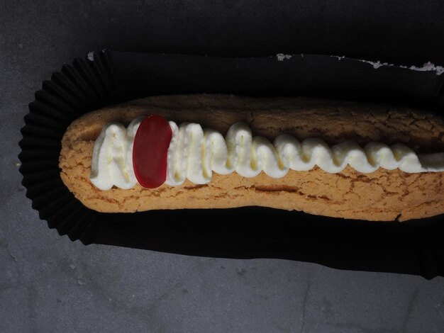 A banana dog with a red topping is on a black surface.