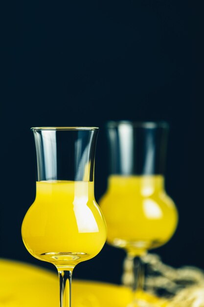 Banana flavoured liqueurs which French call creme de banana in grappas wineglass on dark concrete surface European aperitif drink Selective focus shallow depth of the fields copy space