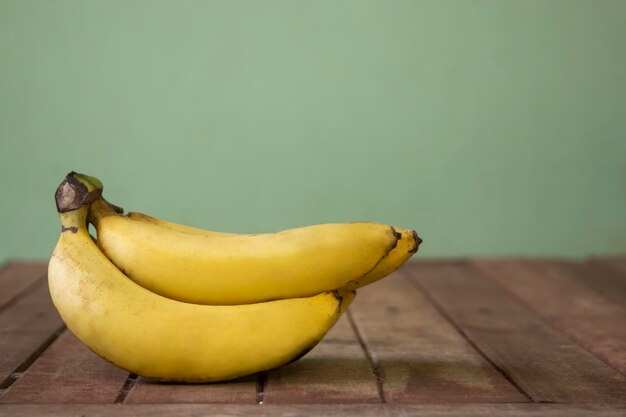 Banana fruit with wooden table on blurred green background