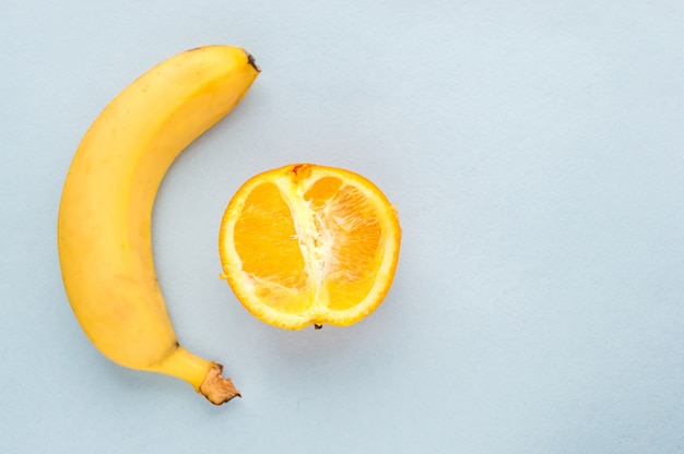 Banana and half an orange on a blue background. Concept sex. Concept penis and vagina.