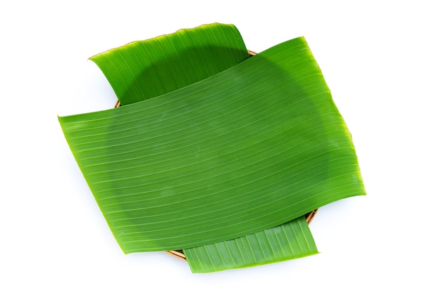 Banana leaves in bamboo basket on white background.