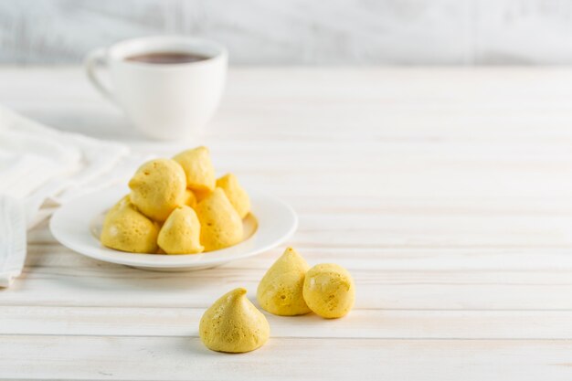 白いプレートと明るい背景にお茶のカップでバナナのメレンゲ。シュガーフリー