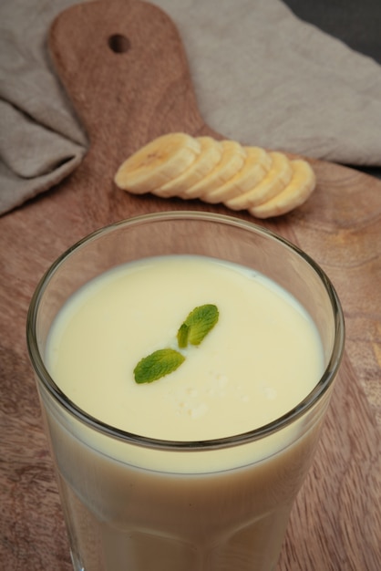 Banana milkshake with mint on wooden chopping board and linen tea towel