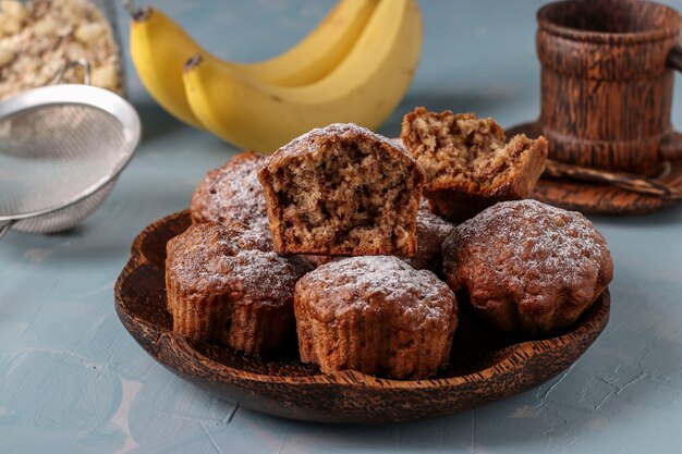 Banana muffins with oatmeal flakes sprinkled with icing sugar on a coconut plate