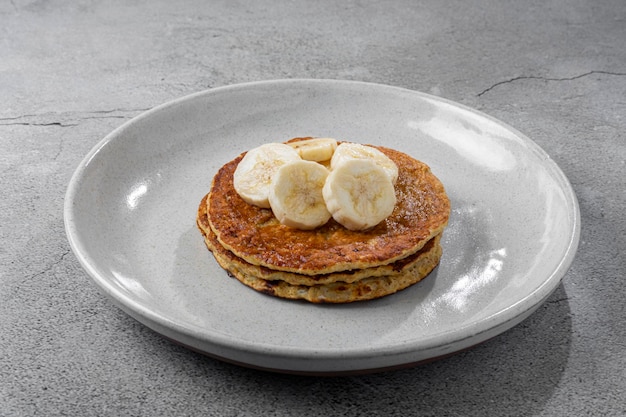 Frittelle di avena alla banana condite con banane a fette e miele