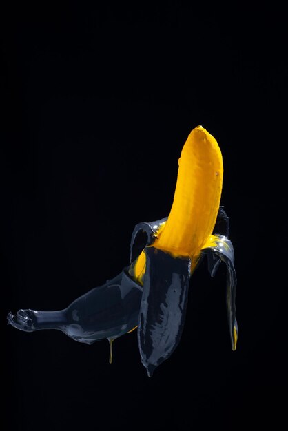 Photo banana paint yellowblack painted banana on a black background levitation