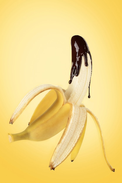 Photo banana poured with liquid chocolate on yellow background