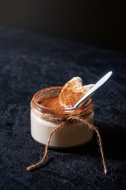 Banana pudding with cocoa powder on dark background