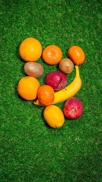 Banana red apple and different fruits laying on grass flat lay Space for text