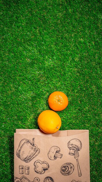 Banana red apple and different fruits with craft paper bag laying on grass flat lay Space for text Zero waste concept