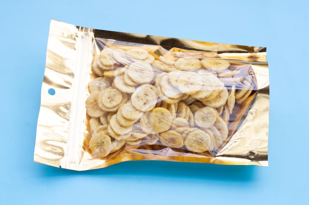 Banana slice chips in package bag on blue background