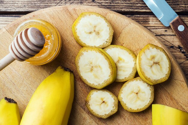 Banana and sliced banana into pieces with honey on wooden table,