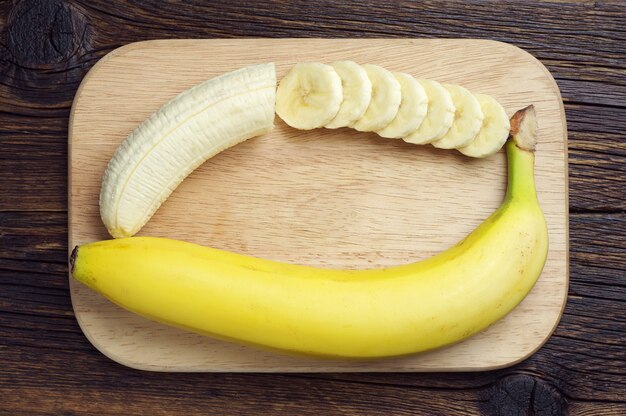 Banana and a sliced on cutting board, top view