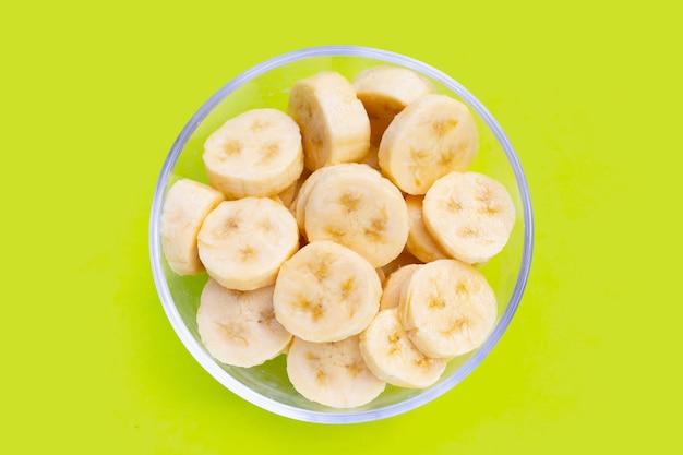 Banana slices in glass bowl on green background
