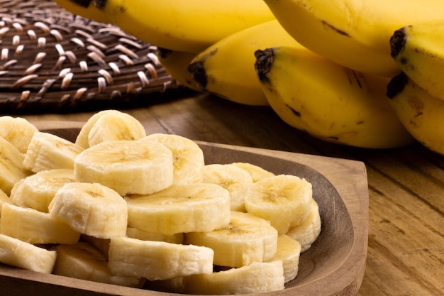 Banana slices in rustic pot with bunch of bananas in the background