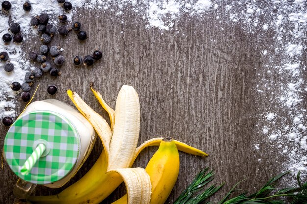 Banana smoothie and fresh banana on wooden table