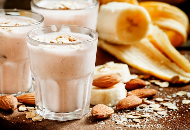 Banana smoothie with milk oatmeal and almonds on the old wooden background selective focus