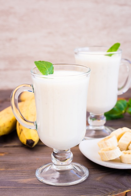 Banana smoothie with mint leaves in glasses on a wood table