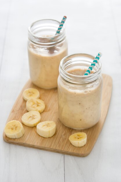 Banana smoothies in jar on white wooden table