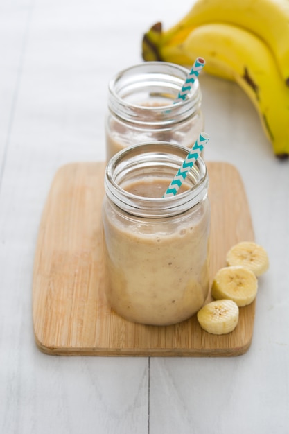 Photo banana smoothies in jar on white wooden table