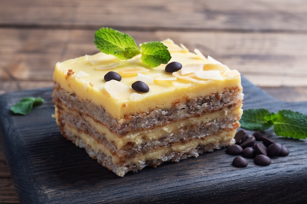 Banana sponge cake with nuts and chocolate drops. Delicious sweet dessert for tea, wooden background.