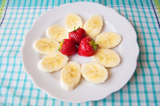 Banana and strawberries on a white plate and a colorful napkin