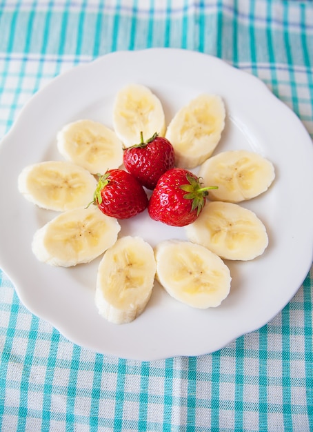 Banana and strawberries on white plate and a colorful napkin