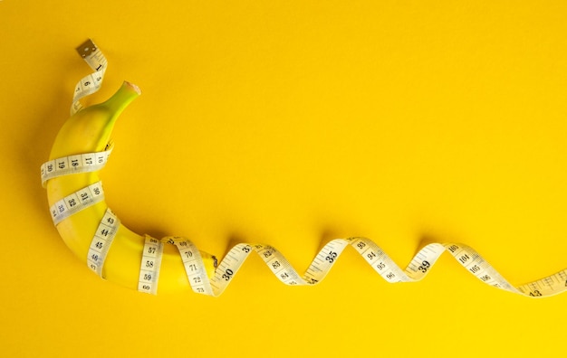 banana and tape measure on yellow background diet concept