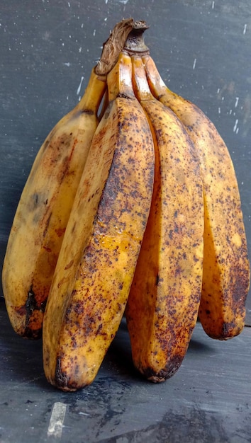 Foto una banana con un primo piano su sfondo nero un frutto di banana dal colore giallo dorato con alcune macchie che indicano che il frutto è maturo