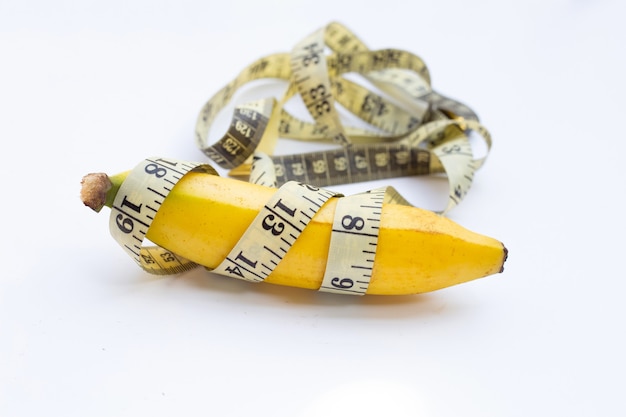 Banana wrapped in measuring tape on white background.