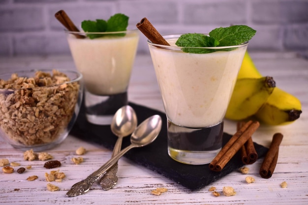 Banana yogurt with cinnamon and granola in glasses.