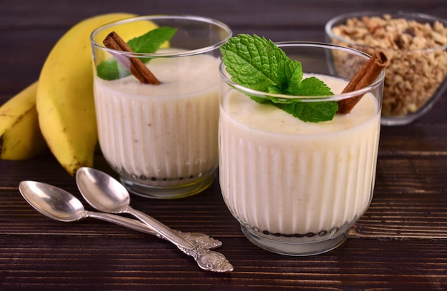 Banana yogurt with cinnamon and muesli on a wooden background.