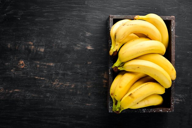 Banane su una superficie di legno nera frutti tropicali vista dall'alto spazio di copia gratuito