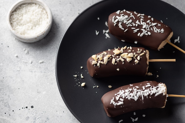 Bananas in dark chocolate with nuts and coconut Frozen dessert