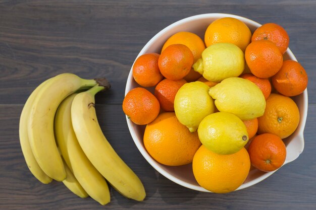 Bananas next to a fruit bowl with citrus fruits