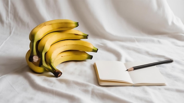 Photo bananas notebook and pencil on white backdrop