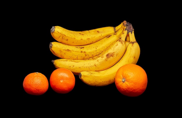 Bananas orange and two tangerines on a black background