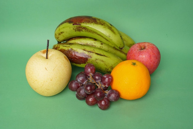 bananas, oranges, apples, pears and grapes isolated on green background