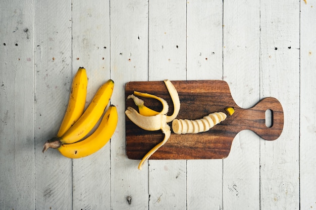 Foto banane in un tavolo in legno bianco e un tagliere