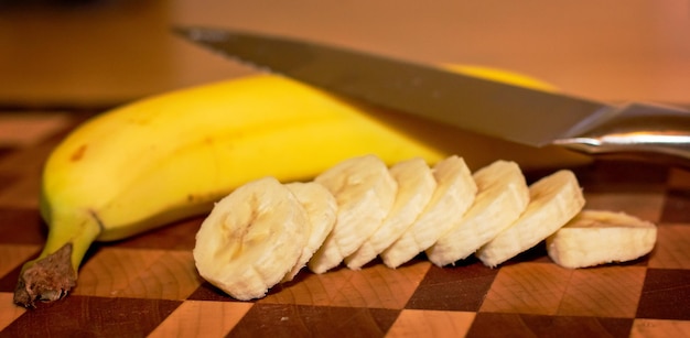 Photo bananas with knife on cutting board