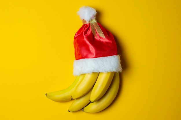 Bananas on yellow background in santa claus hat